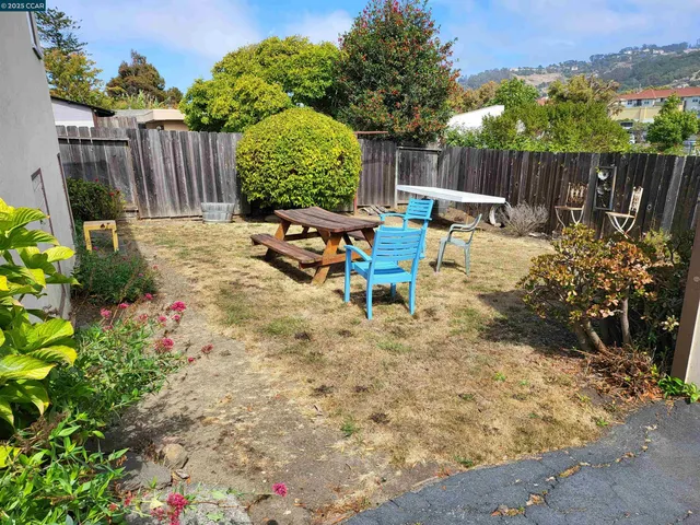 a view of a backyard with chairs potted plants and wooden fence