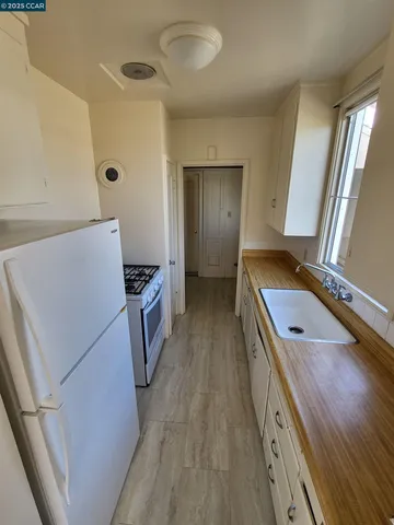 a kitchen with a refrigerator a sink and wooden floor