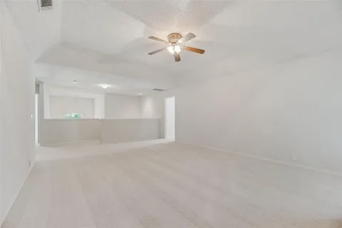 an empty room with windows and chandelier fan