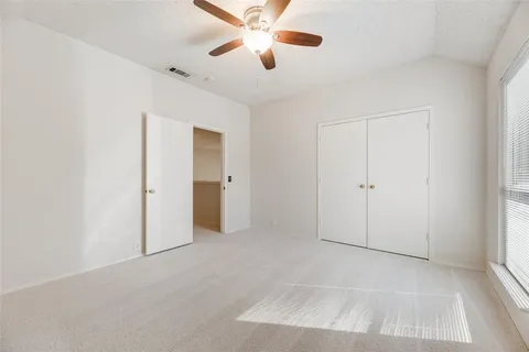 an empty room with a window and a fan