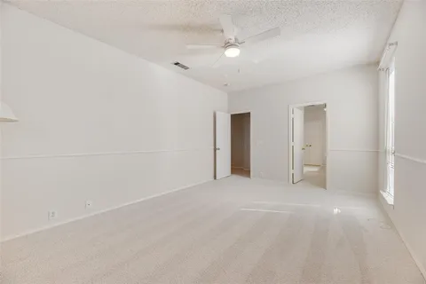 an empty room with windows and chandelier fan