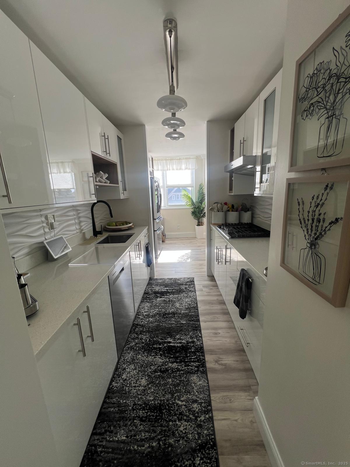 2370 North Avenue, Unit 3F Bridgeport, CT 06604 - Photo 6 of 25 a large white kitchen with stainless steel appliances a stove a sink a refrigerator cabinets and wooden floor