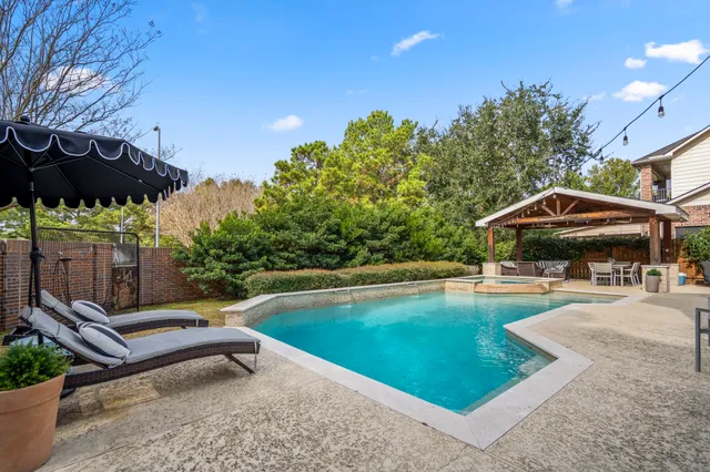 a view of pool with lawn chairs under an umbrella