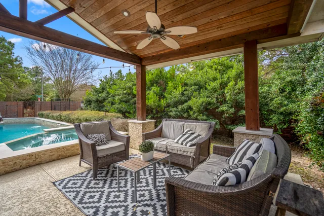 a view of patio with lawn chairs and couches with wooden floor and fence