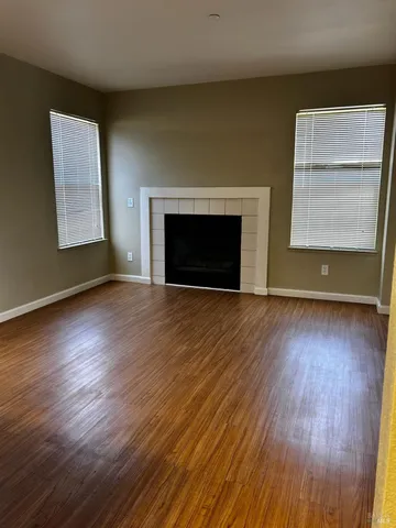 an empty room with wooden floor fireplace and window