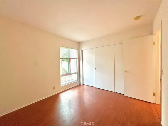 an empty room with wooden floor and windows with curtains