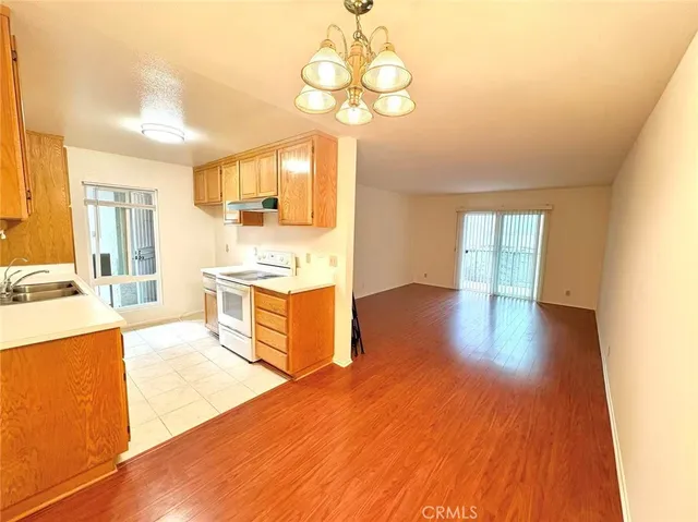 a large kitchen with wooden floor and stainless steel appliances
