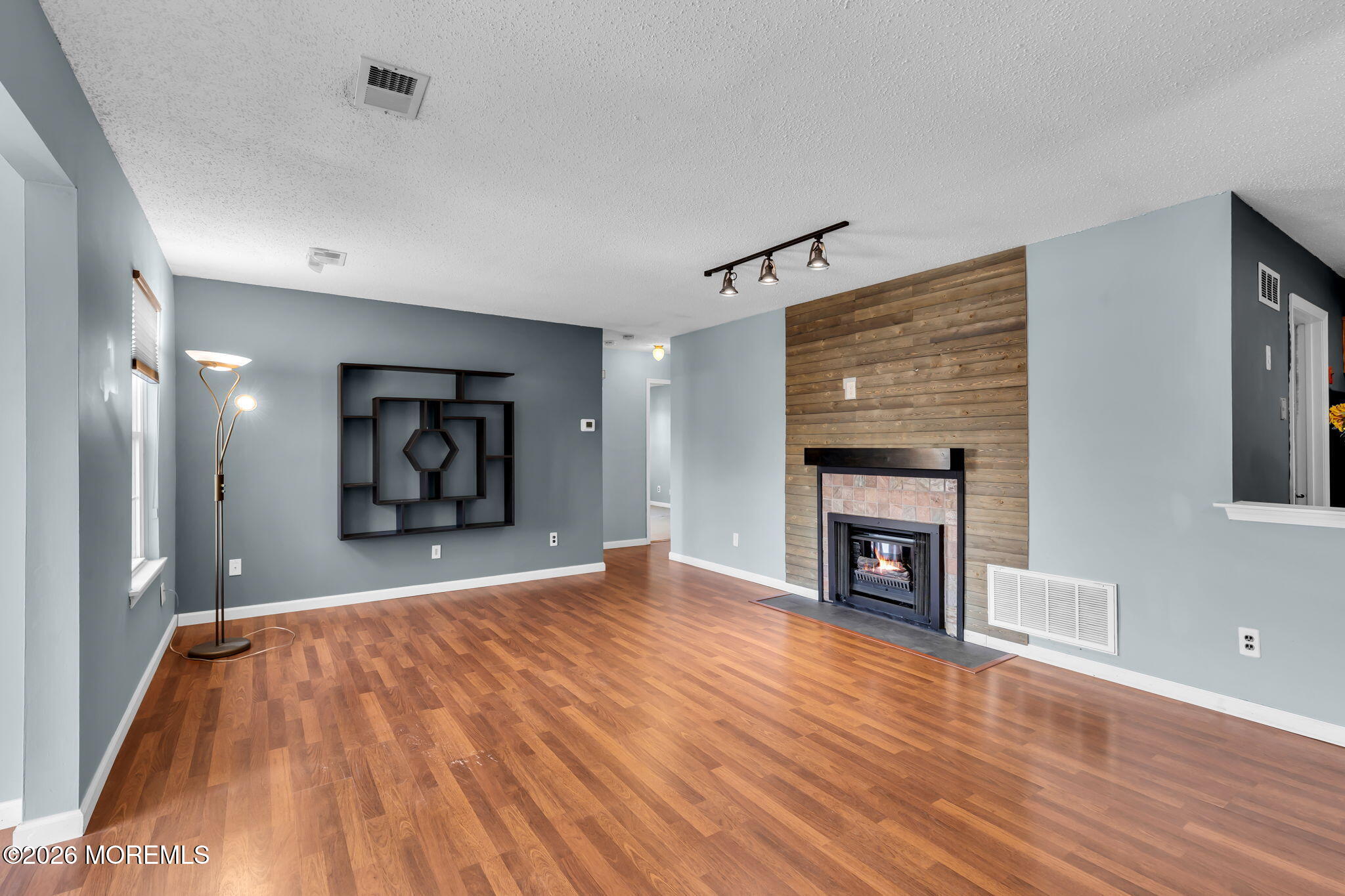 a big room with wooden floor a fireplace and window