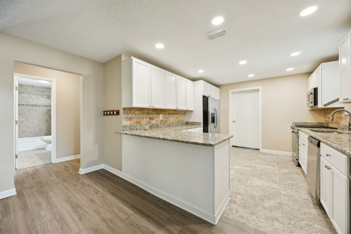 87529 Roses Bluff Road Yulee, FL 32097 - Photo 15 of 38 a kitchen with stainless steel appliances granite countertop a stove a sink and a refrigerator