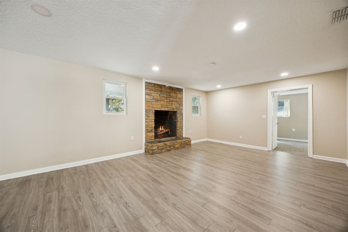87529 Roses Bluff Road Yulee, FL 32097 - Photo 10 of 38 an empty room with wooden floor and fireplace