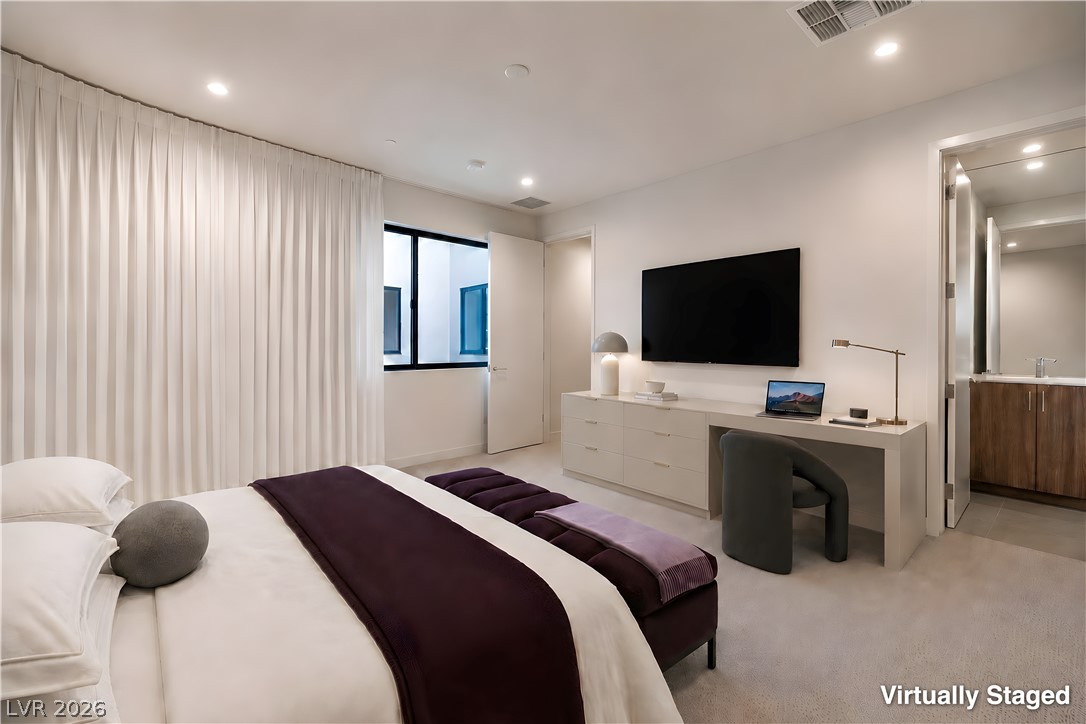 25 Falling Ridge Lane Henderson, NV 89011 - Photo 27 of 48 Well-lit primary bedroom features soft carpet and direct access to an ensuite bathroom, offering serene relaxation.