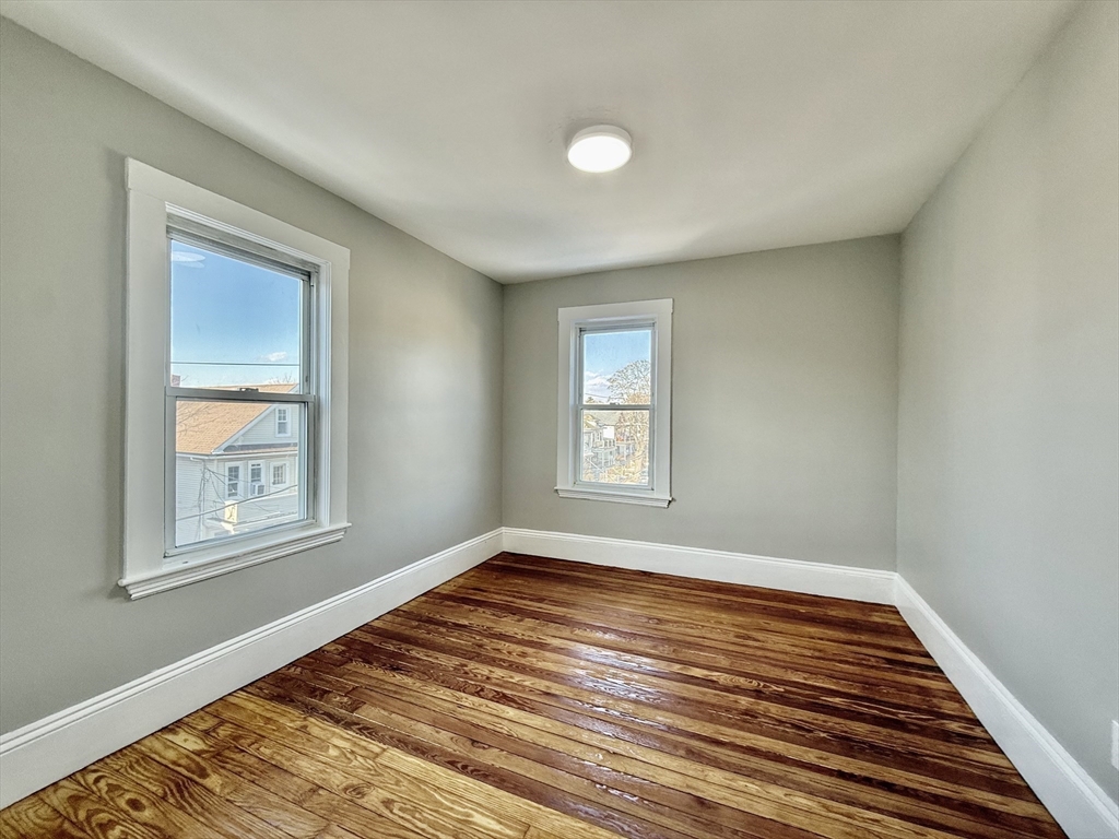 69 Conwell Avenue, Unit 2 Somerville, MA 02144 - Photo 7 of 14 a view of an empty room with wooden floor and a window