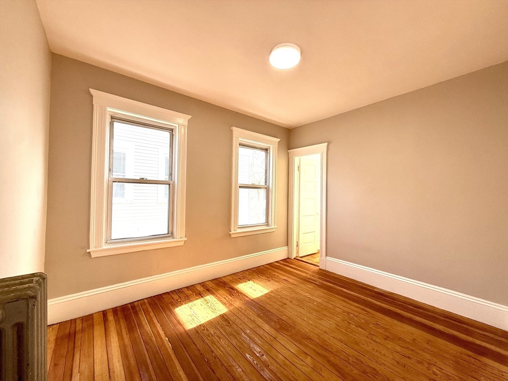 69 Conwell Avenue, Unit 2 Somerville, MA 02144 - Photo 9 of 14 a view of an empty room with wooden floor and a window