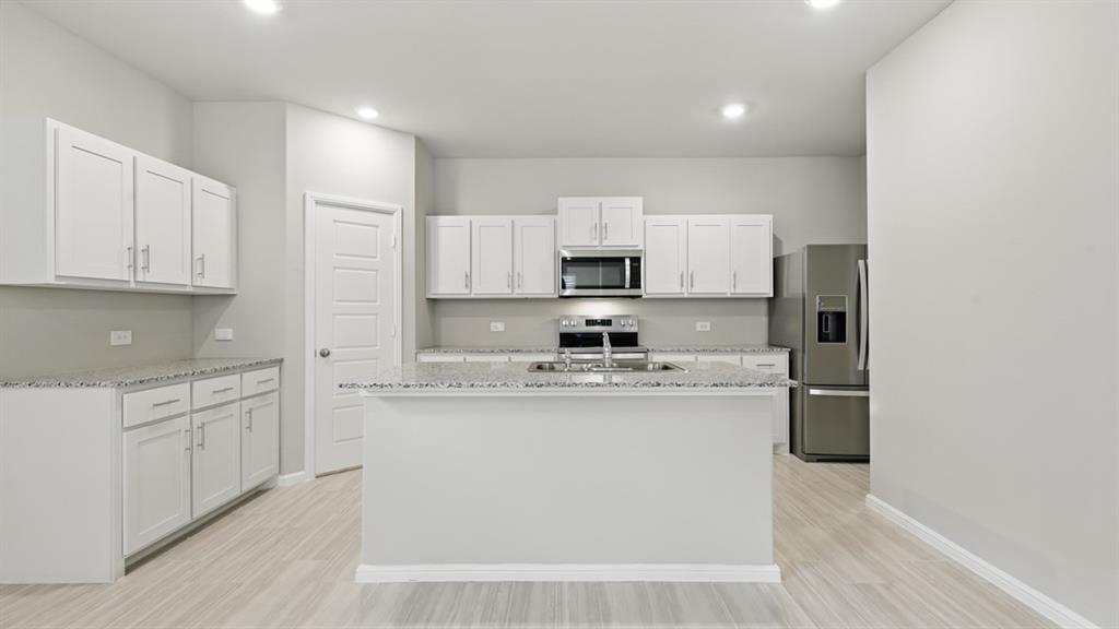 a kitchen with stainless steel appliances granite countertop white cabinets a sink a stove a refrigerator and white cabinets