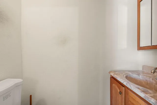 a bathroom with a granite countertop sink and a toilet