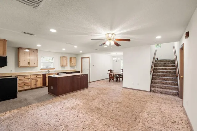 a large kitchen with stainless steel appliances kitchen island granite countertop a large counter top and chairs