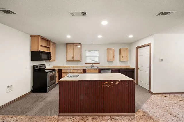 a large kitchen with kitchen island a stove a sink a refrigerator and a microwave