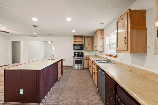 a large kitchen with stainless steel appliances lots of counter space and wooden floor