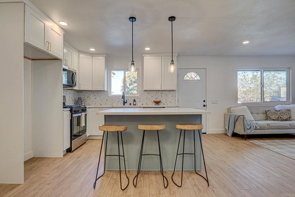 4205 Rene Drive San Diego, CA 92154 - Photo 11 of 24 a kitchen with stainless steel appliances granite countertop a stove a sink a oven a refrigerator with white cabinets and wooden floor