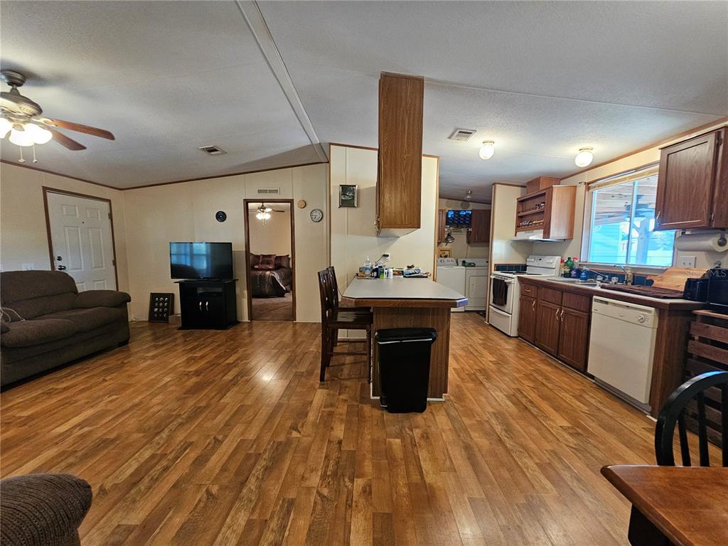 14381 Camp Mack Road Lake Wales, FL 33898 - Photo 11 of 52 a large open kitchen with stainless steel appliances kitchen island granite countertop a refrigerator a stove a sink a dining table and chairs with wooden floor