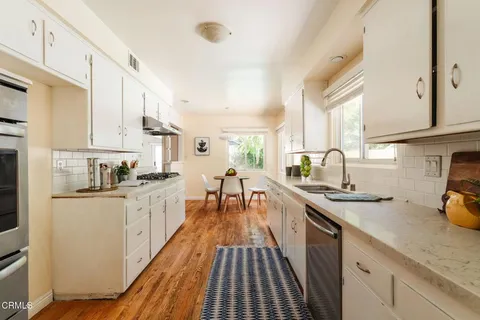 a kitchen with stainless steel appliances a sink a stove top oven a counter space and cabinets