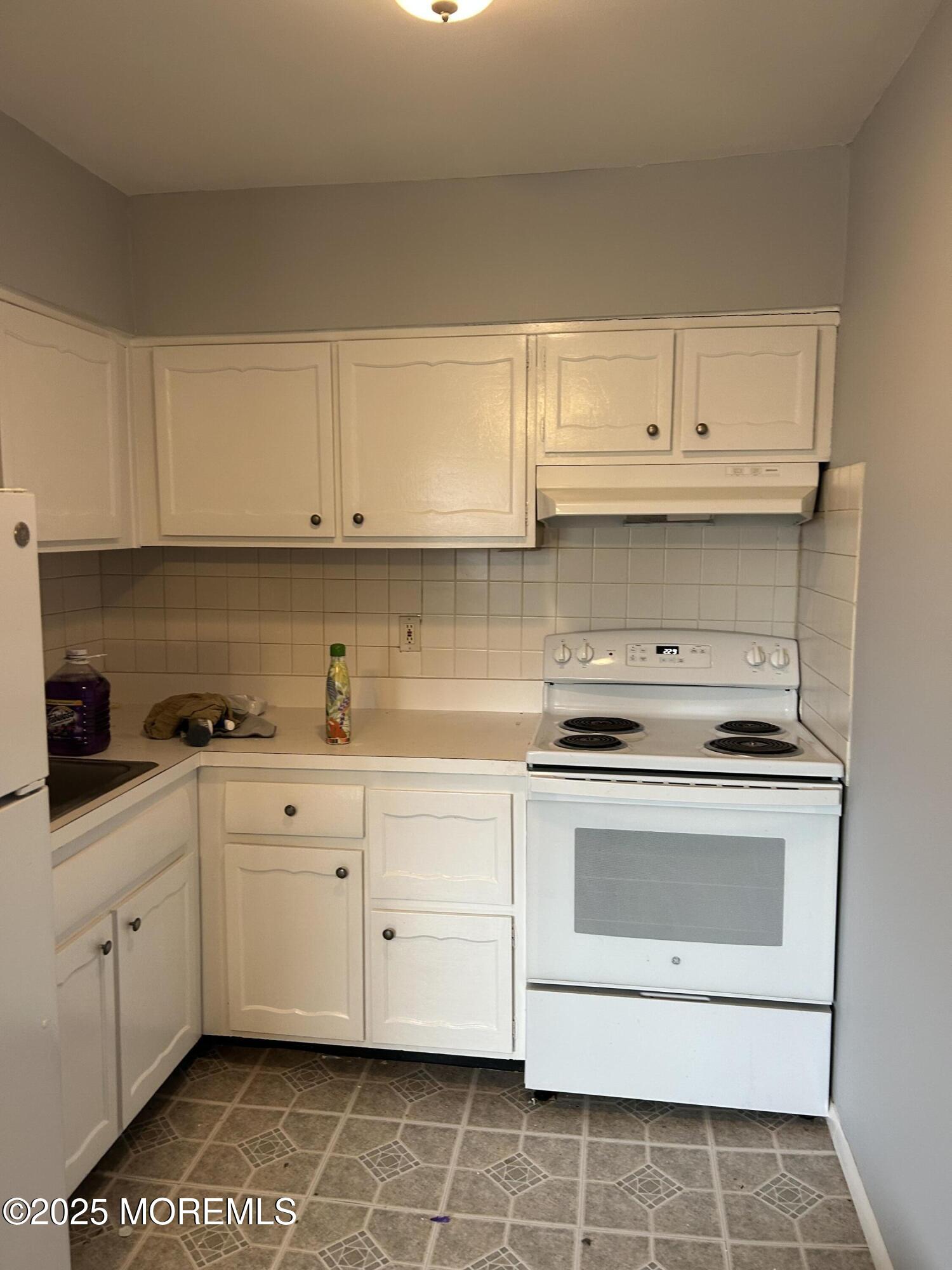240 South Lincoln Avenue, Unit 16 Elberon, NJ 07740 - Photo 4 of 7 a kitchen with granite countertop white cabinets and white appliances