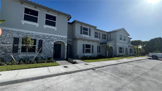 a front view of a building with garden and trees