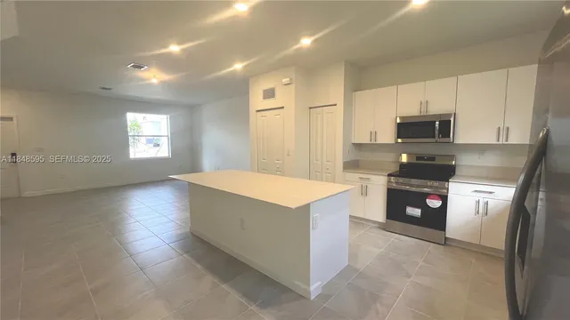 a kitchen with stainless steel appliances a stove a sink a microwave and a refrigerator