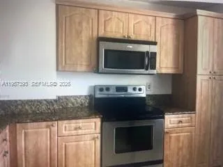 a kitchen with granite countertop white cabinets and stainless steel appliances