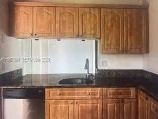 a kitchen with granite countertop a sink cabinets and stainless steel appliances