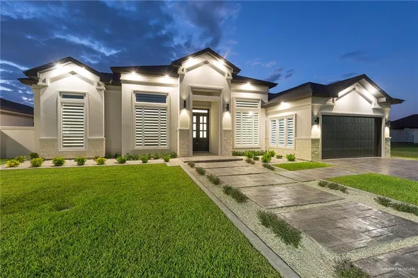 a view of a house with large windows and a yard with table and chairs