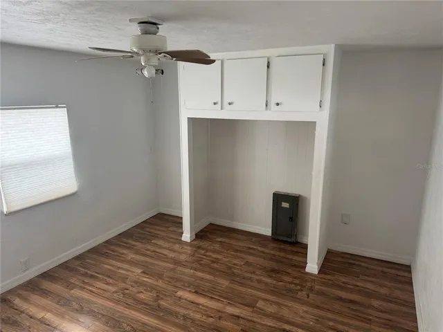 an empty room with wooden floor and cabinet