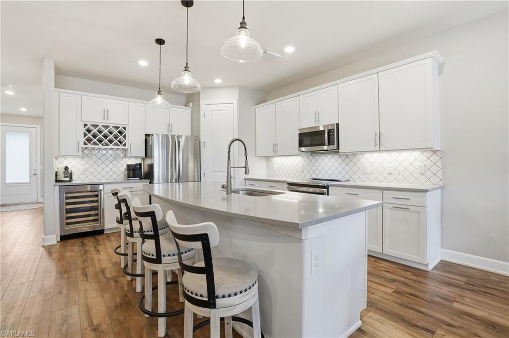 19906 Beverly Park Road Estero, FL 33928 - Photo 16 of 50 a kitchen with stainless steel appliances granite countertop a stove top oven a sink a dining table and chairs with wooden floor