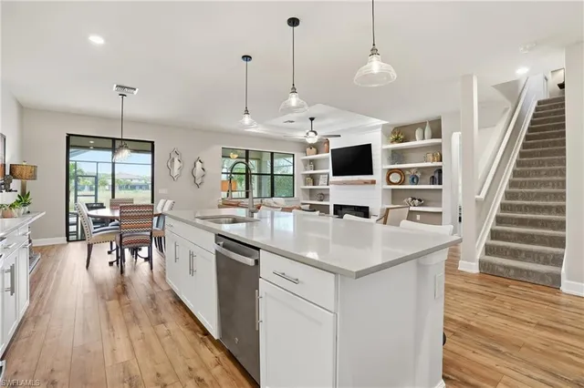 a kitchen with stainless steel appliances granite countertop a sink a stove a refrigerator and island with wooden floor