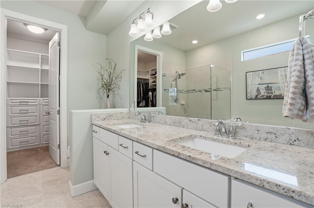 19906 Beverly Park Road Estero, FL 33928 - Photo 30 of 50 a bathroom with a granite countertop sink a large mirror and a shower
