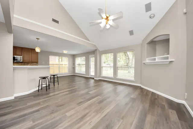 an empty room with wooden floor and windows