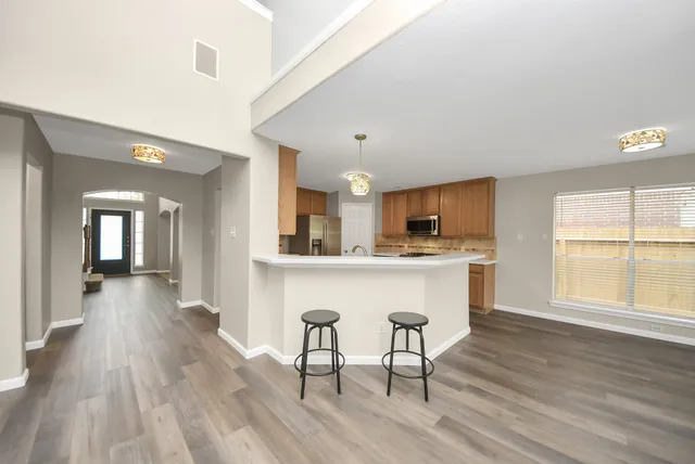 a kitchen with stainless steel appliances granite countertop a living room dining room and wooden floor