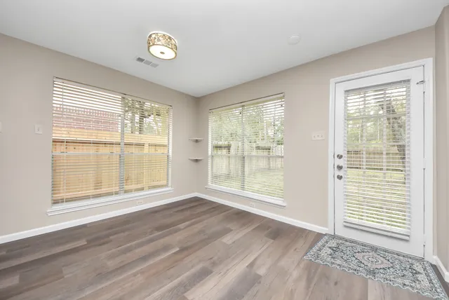 a view of an empty room with a window and wooden floor