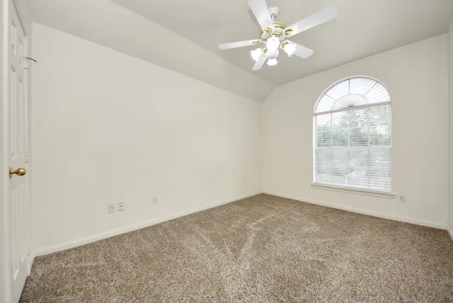 an empty room with windows and ceiling fan