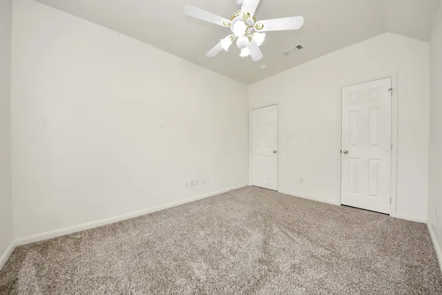 an empty room with a chandelier fan and closet