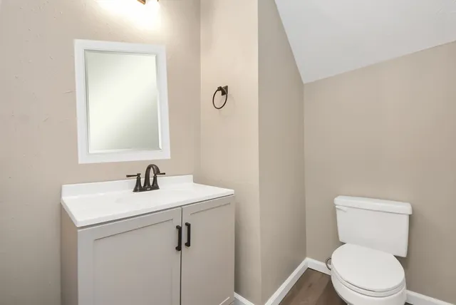a bathroom with a toilet sink vanity and mirror