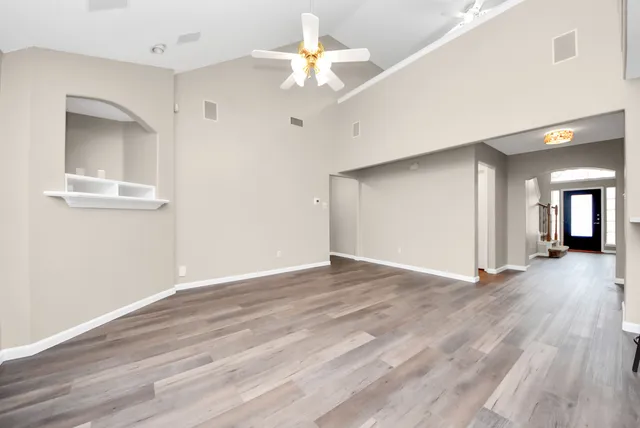 a view of an empty room with window and wooden floor