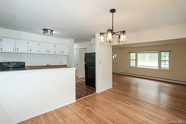 a view of a kitchen with a refrigerator wooden floor and a window