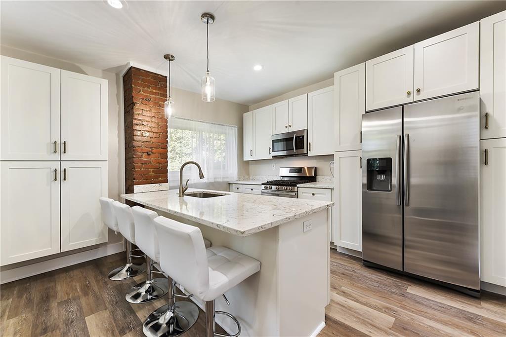 22 Millbridge Street Pittsburgh, PA 15210 - Photo 10 of 25 a kitchen with stainless steel appliances a refrigerator a sink a stove a table and chairs