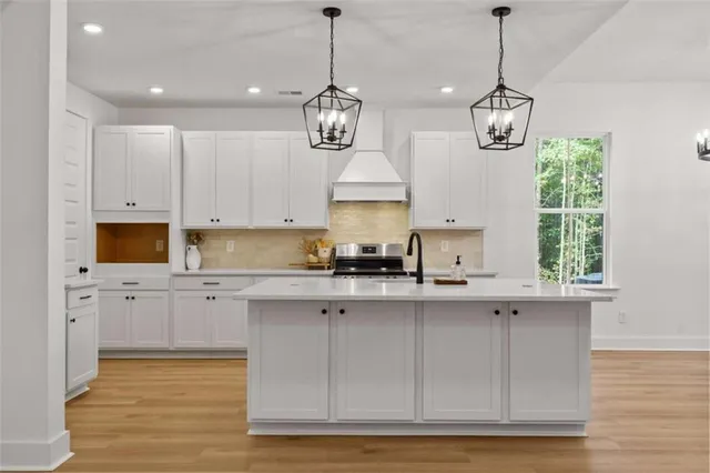 a kitchen with stainless steel appliances a sink a stove a refrigerator and white cabinets