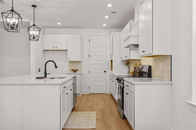 a kitchen with a sink dishwasher and white cabinets with wooden floor
