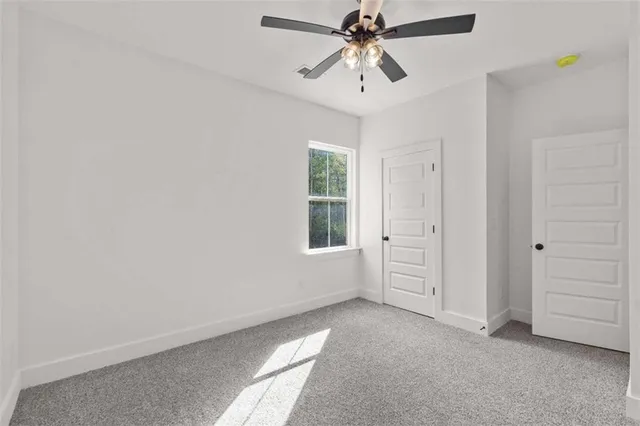 an empty room with windows and chandelier fan