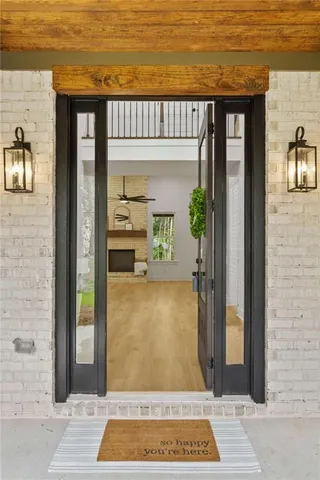 a view of a hallway to a livingroom with wooden floor and staircase