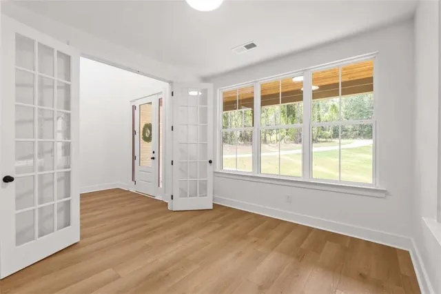 a view of an empty room with wooden floor and a window