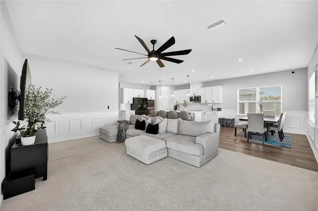 a living room with stainless steel appliances lots of furniture and a refrigerator